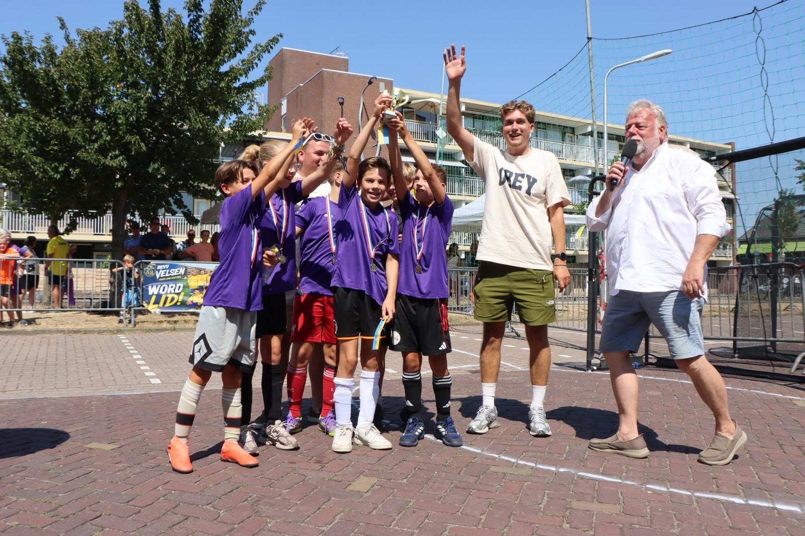 De winnaars van 10 t/m 12 jaar in paarse shirts van Hoveniersbedrijf Goes met de beker